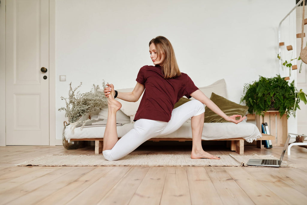 Femme faisant du yoga devant un ordinateur portable